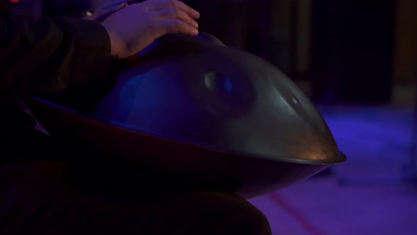 Close up view of musician hands playing handpan drum on big concert hall stage