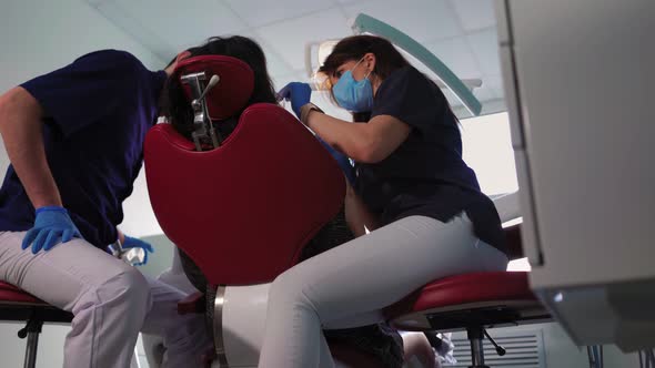 Doctors Dentists Woman and Man in Medical Masks Serve Patient in Dental Clinic