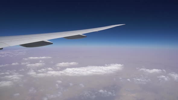 Plane wing over the horizon Blue sky high above the clouds, view from the plane window