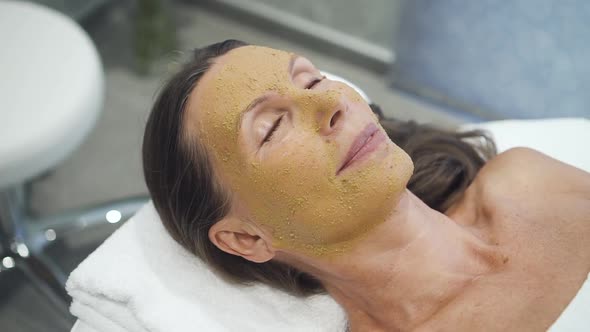 Middle Age Woman Lying in Spa Salon with Mask on Face