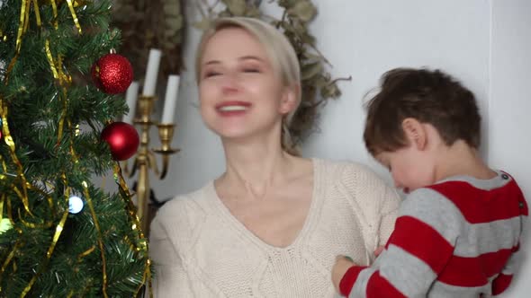 Mother with a son stands next to Christmas tree at home