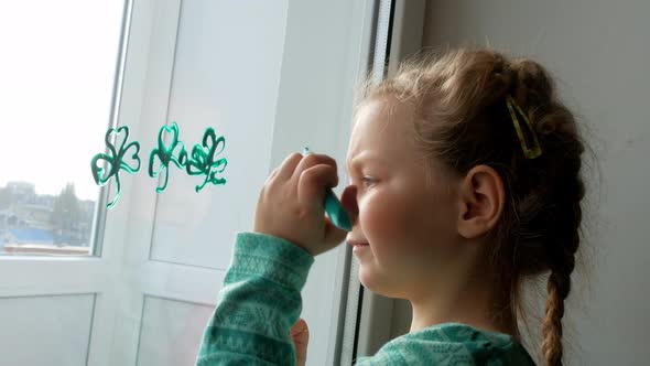 Drawing St.Patrick's Day Child painting green three-leaved shamrocks indoor Little girl draws clover