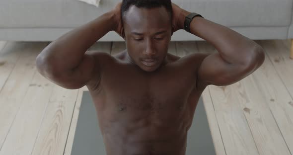 Close Up Portrait of Young Muscular Black Man Practicing Criss Cross Crunches Exercise at Home