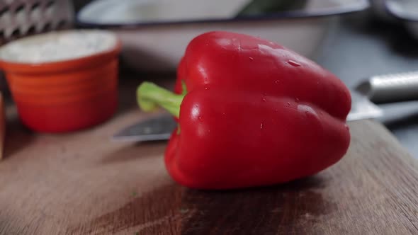 Slow pan slide right to left of red pepper on wooden chopping board. Close up