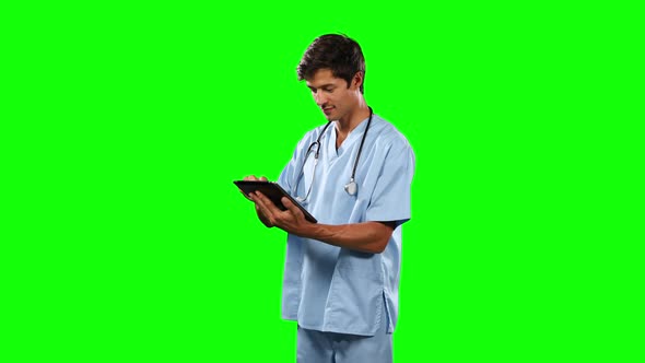 Side view of doctor using his digital tablet with green screen