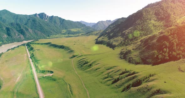 Aerial Rural Mountain Road and Meadow at Sunny Summer Morning. Asphalt Highway and River