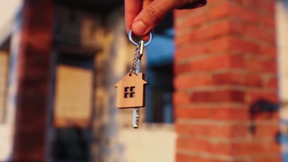 Hand with the key to the future house on the background of a construction site