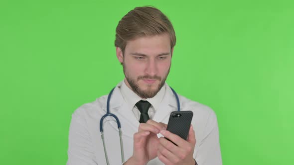 Young Doctor Browsing Smartphone on Green Background
