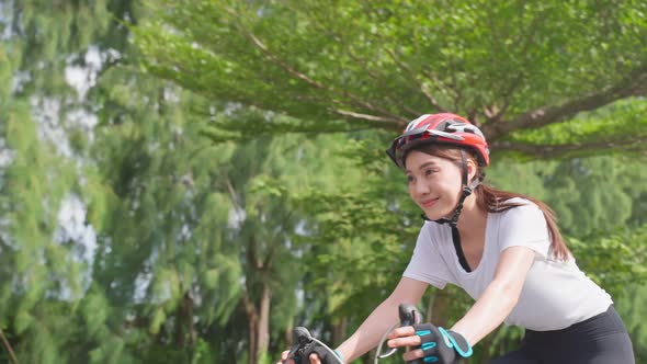 Asian young sport woman riding bicycle in the evening in public park.