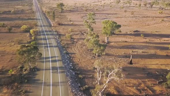 Drone lifting up over road to reveal Australian outback landscape