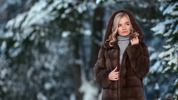 Fashionable Lady Posing in Stylish Brown Hood Fur Coat Snowy Spruce