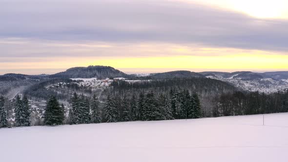 Sunrise over a winter landscape - panning shot over a beautiful snowy white field with hills in the