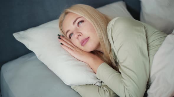 Handsome blond woman waking up and looking at phone in bed