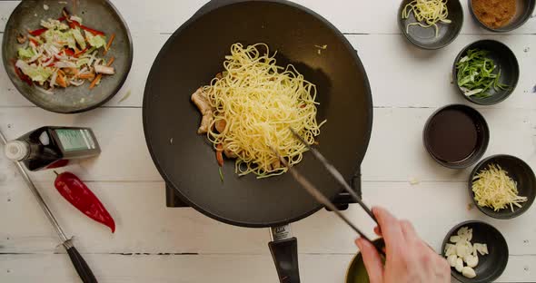 Chef Holding Frying Pan and Falling Wok Noodles with Many Different Veggies