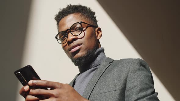 Afro-American Businessman Using Smartphone and Smiling at Camera