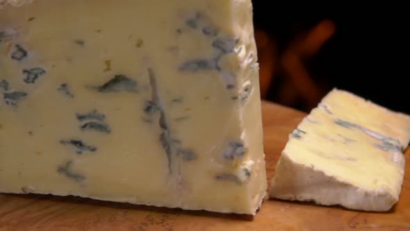 Cut Piece of Cheese with Blue Mold Falls on a Board