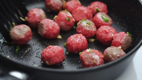 Unrecognizable person cooking meatballs on frying pan with oil