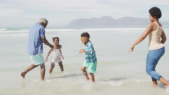 Happy african american couple playing with children on sunny beach