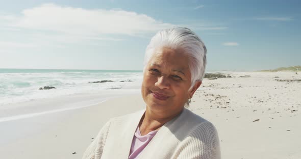 Portrait of senior hispanic woman standing on beach and smiling at camera