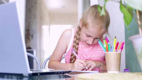 Caucasian Girl Writes in a Notebook Speaking Emotionally to Online Teacher