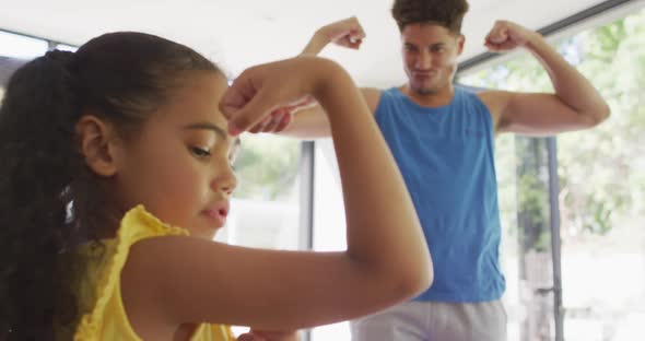 Happy biracial father and daughter doing yoga, stretching together