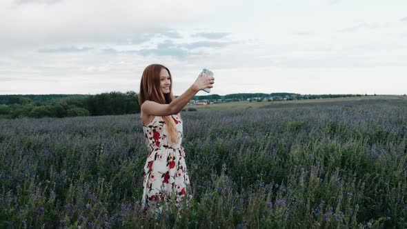 Happy Young Woman Takes Selfie Photo in Beautiful Wild Flowers Field in Summer, Pink and Purple