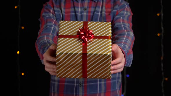 Boy with a Gift Box on Black Background. Gift Box with Ribbon for Happy New Year, Merry Christmas