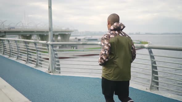 African Man Jogging on Pedestrian Bridge in City