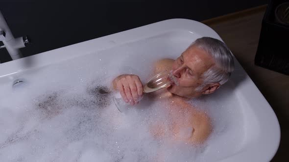 Senior Couple Grandfather and Grandmother Is Taking Foamy Bath Drinking Champagne in Luxury Bathroom