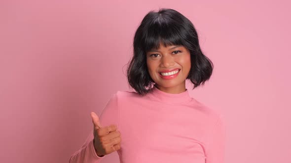 Lovely Mixed Race Young Woman Makes Thumb Up Gesture Approves Ok Over Pink Wall