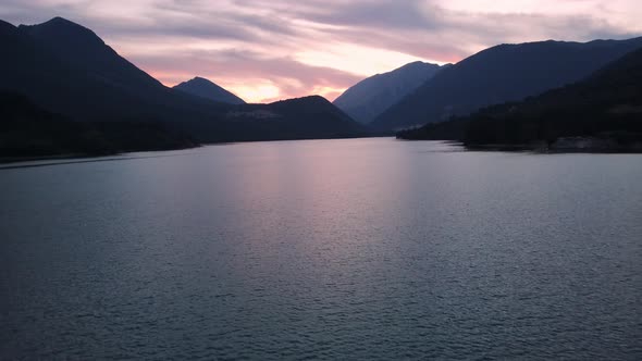 Drone Flies Over a Lake in the Mountains at Sunset