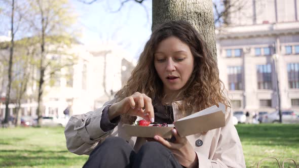 Curlyhaired Woman Eats Cake with Strawberry and Cherry