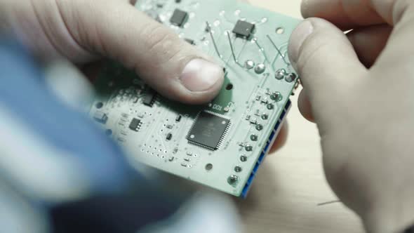 A Worker Is Working on the Creation of an Electronic Board. Close-up.