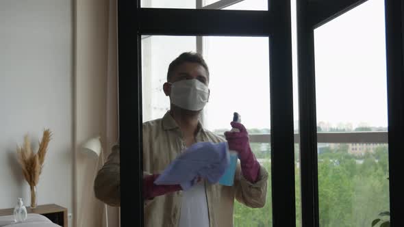 Home window cleaning disinfection. Man in a medical mask cleans windows during quarantine.