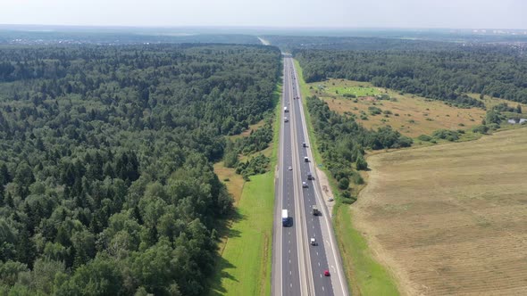 Flying Over a Twoway Road Between Forests and Fields Along Which Many Cars Travel