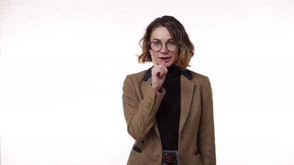 Beautiful Young Brunette Woman in Glasses with Finger on Lips Showing Silent or Hush Gesture and