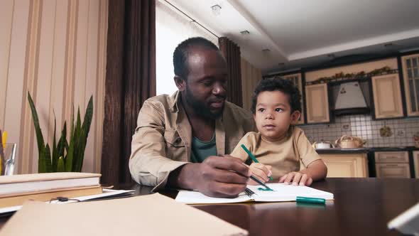 African American father drawing with his child in notebook