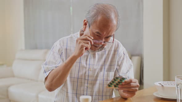 Asian Senior elderly male wearing eyeglasses patient eating on table at nursing home care.