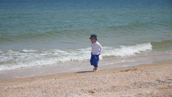 Child Boy in Blue Pants and a Panama Hat Runs