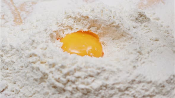 Yolk Falls Into the Flour on a Wooden Table