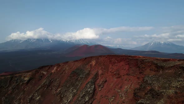 red mountain with a view of snow volcanoes