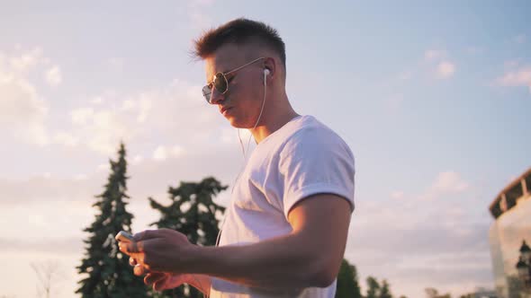 Handsome Young Hipster Man Using Smartphone Outdoors in Park