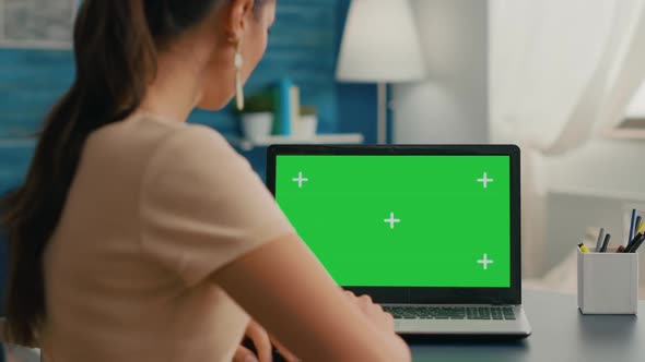 Back Shot of Freelencer Woman Looking at Laptop with Mock Up Green Screen