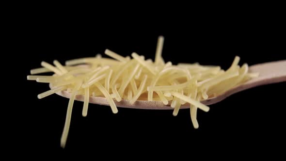 A full wooden spoon of thin uncooked broken spaghetti