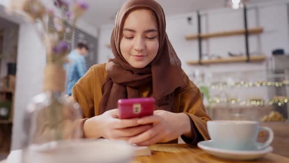 Portrait of Excited Middle Eastern Young Woman Using Social Media on Smartphone Messaging Online