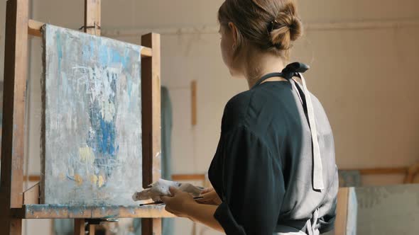 Artist with Hair Bun Applies Paint on Canvas Drawing Picture