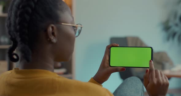 African American Woman Scrolling and Tapping on Green Screen of Mobile