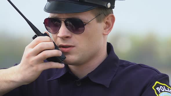 Determined Police Officer Communicating on Walkie-Talkie, Exchanging Information