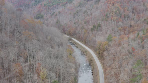 Drone shot of river and road from high altitude flying downstream in late fall in western North Caro