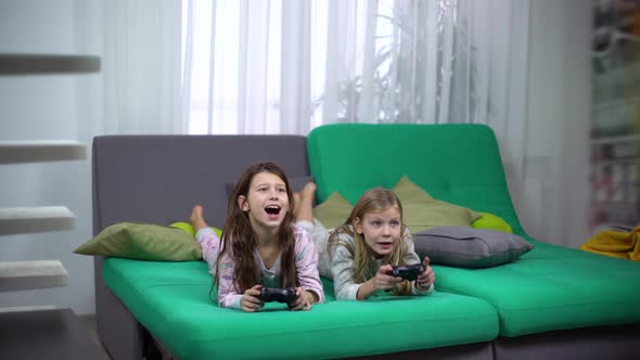 Girls Lying on Sofa and Playing with Game-Pads